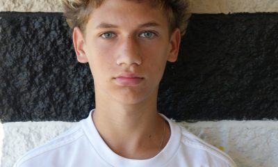Young man in white soccer uniform posing for a portrait.