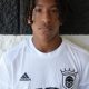This is a portrait of a person wearing a soccer uniform. The individual has dreadlocks and is looking directly at the camera.