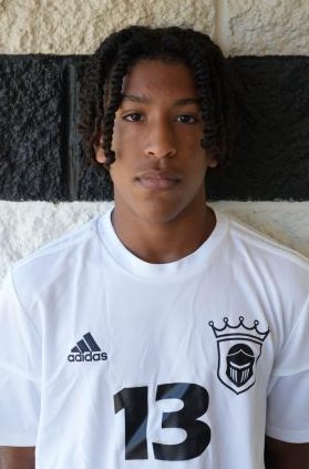 This is a portrait of a person wearing a soccer uniform. The individual has dreadlocks and is looking directly at the camera.