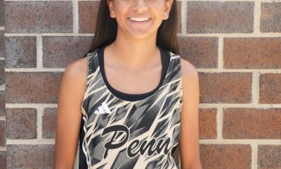 Girl posing in front of brick wall, smiling at camera.