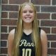 Girl in black jersey posing for picture against brick wall.