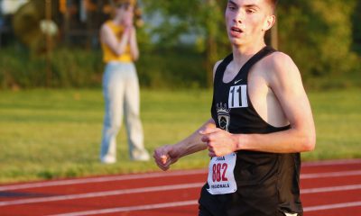 Man in a track uniform running on a track.