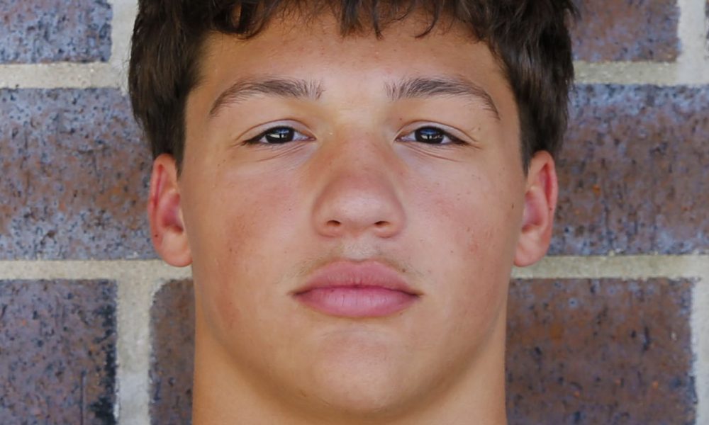 Young man posing for a portrait against brick wall.