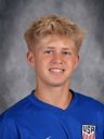 Young male athlete in blue uniform smiling at camera.