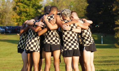 Group of men in checkered shorts huddled together on a field.