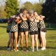 Group of men in checkered shorts huddled together on a field.