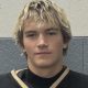This is a portrait of a young man with blonde hair wearing a hockey uniform. He has a serious expression on his face and is