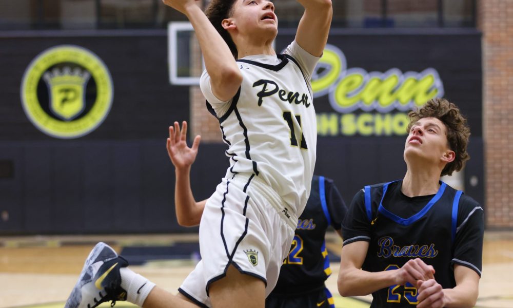Basketball player in mid-air shooting a basketball during a game.