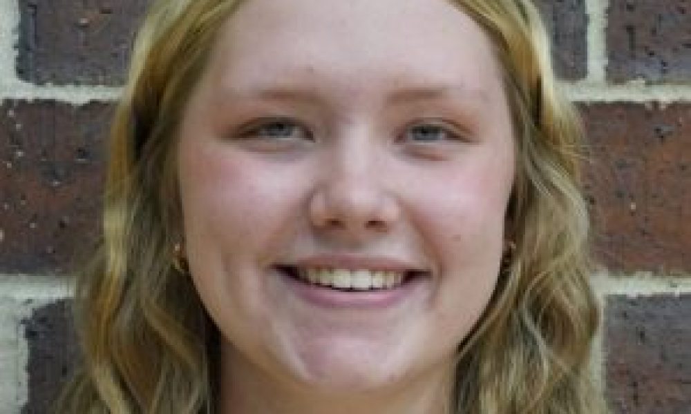 Woman wearing a black jersey with yellow lettering.