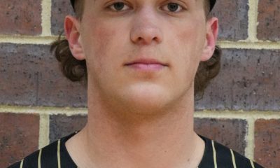 Baseball player posing in front of brick wall.