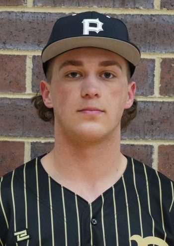 Baseball player posing in front of brick wall.