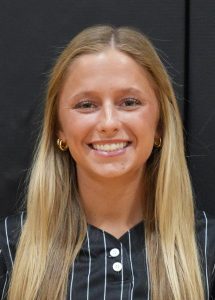 Woman in black and white striped shirt smiling at camera.