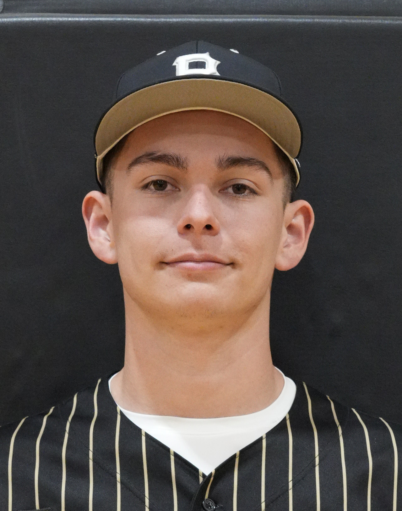 This is a portrait of a young male athlete wearing a baseball uniform, posing for a team photo.