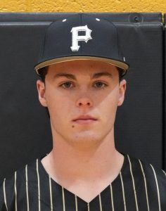 Man wearing a baseball cap with the letter p on it, posing for a portrait in a school uniform.