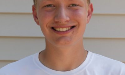 Young man in white jersey smiling at camera.