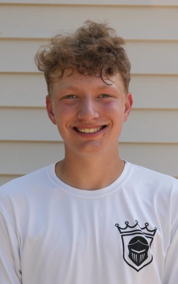 Young man in white jersey smiling at camera.
