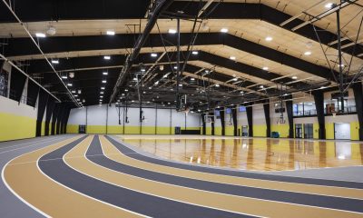 An empty basketball court with yellow walls and a black-and-yellow track.