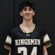 This is a person wearing a black jersey with white lettering and numbers, posed in front of a basketball hoop.