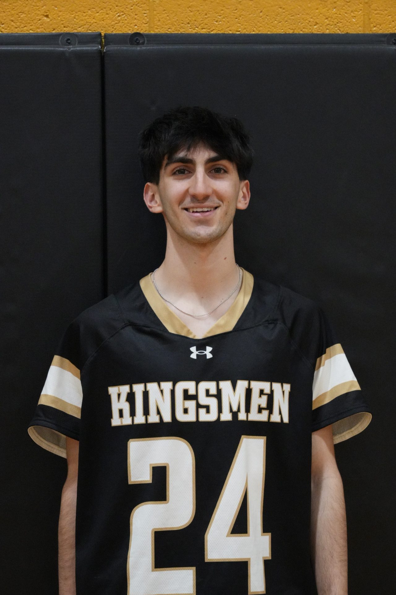 This is a person wearing a black jersey with white lettering and numbers, posed in front of a basketball hoop.