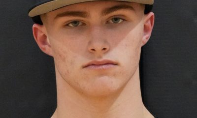 Man wearing a black baseball cap with a white logo on the front, posing for a portrait.