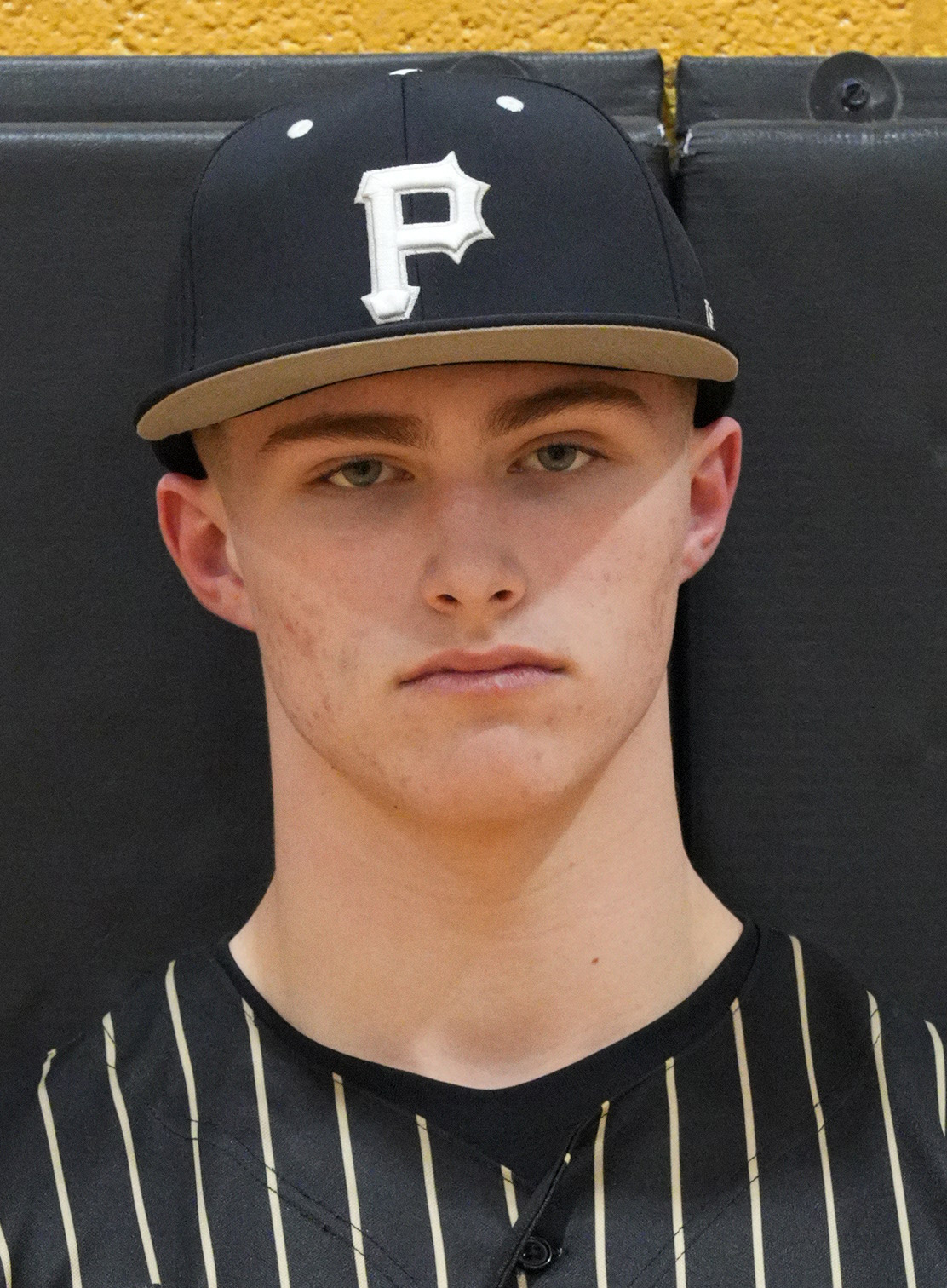 Man wearing a black baseball cap with a white logo on the front, posing for a portrait.