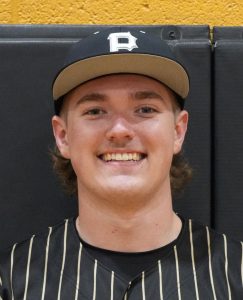 Baseball player in a black and gold uniform smiling at the camera.
