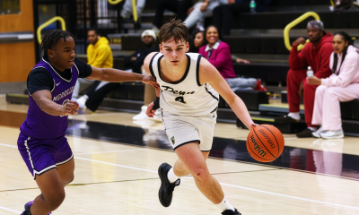 Man in a black shirt running on a basketball court.