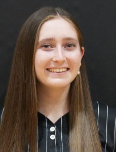 Woman in black and white striped shirt smiling at camera.