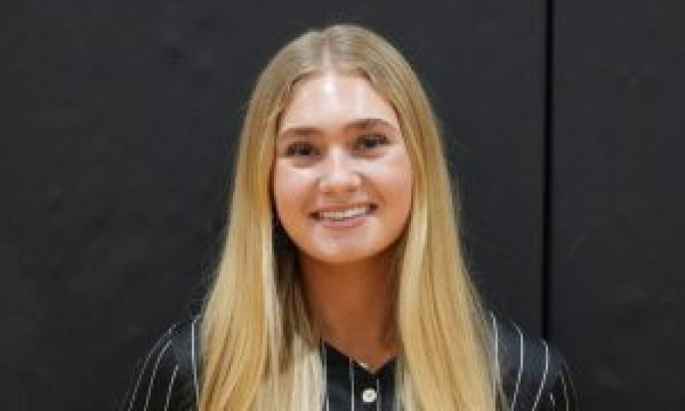 Woman in a black baseball uniform posing for a photo.