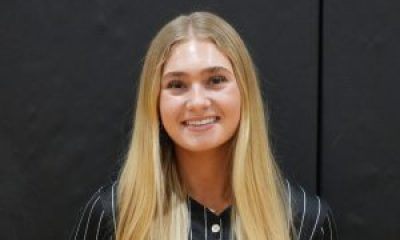 Woman in a black baseball uniform posing for a photo.