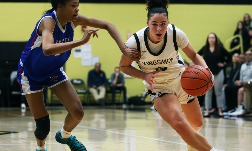 Two athletes competing in a basketball game on an indoor court.