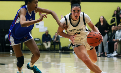 Two athletes competing in a basketball game on an indoor court.