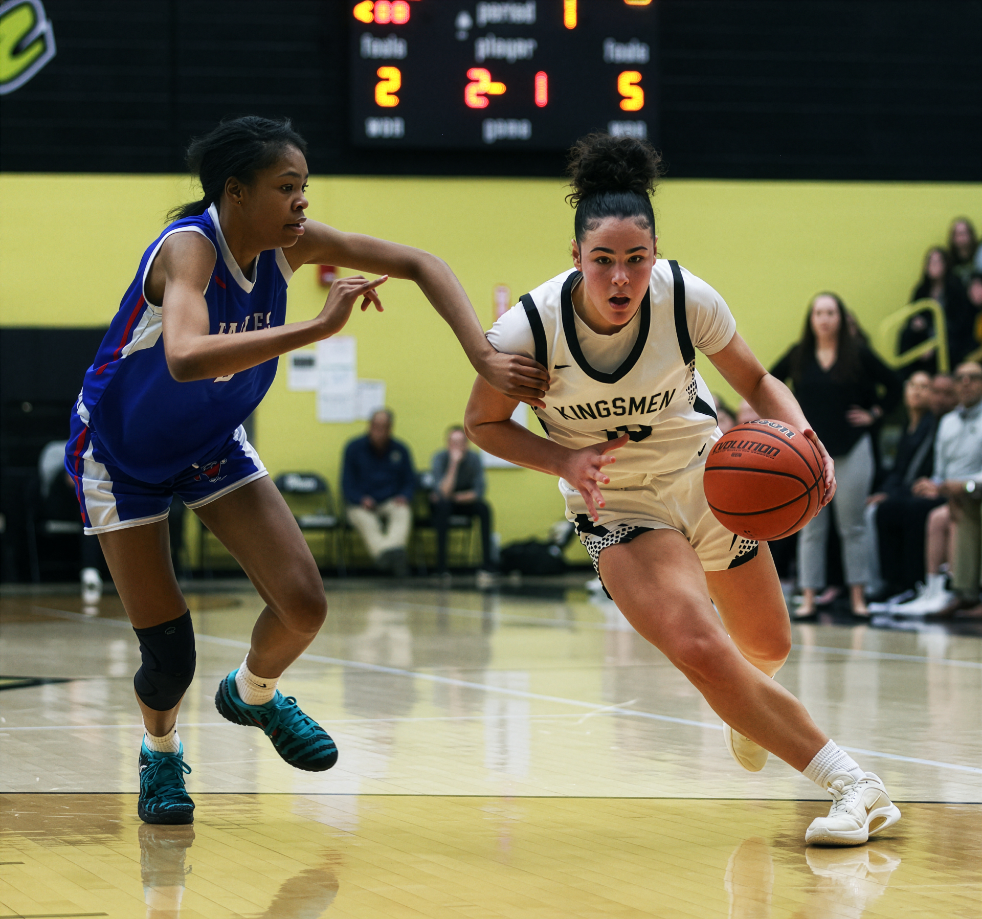 Two athletes competing in a basketball game on an indoor court.