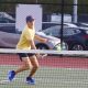 A tennis player hits a tennis ball on a court.