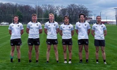 Group of young men in uniforms posing for a team picture on a field.