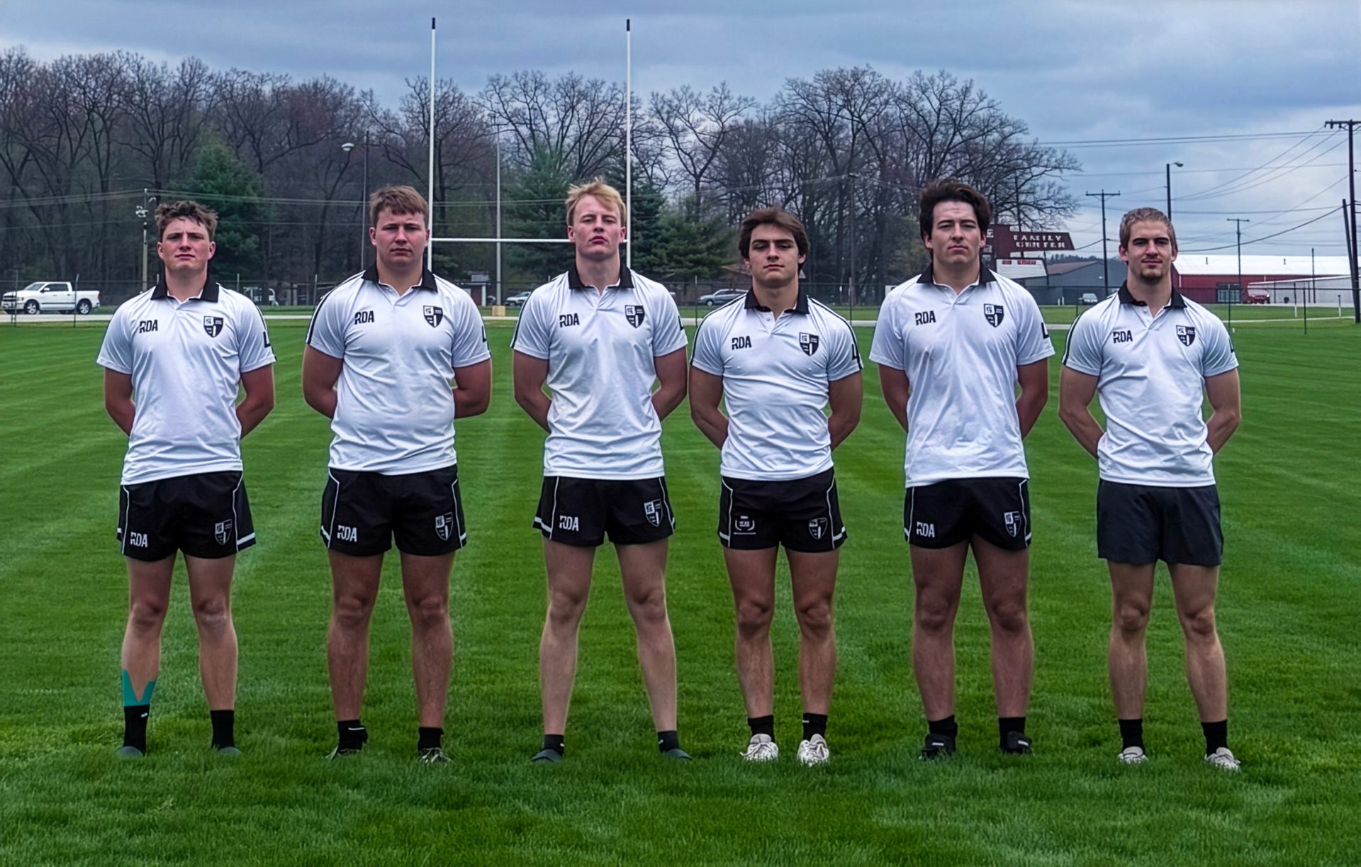 Group of young men in uniforms posing for a team picture on a field.