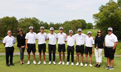 The golf team poses together on a green course.