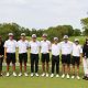 The golf team poses together on a green course.