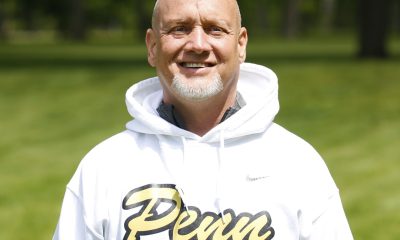 Man in white sweatshirt posing for picture on golf course.