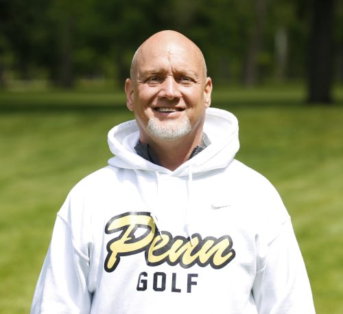 Man in white sweatshirt posing for picture on golf course.