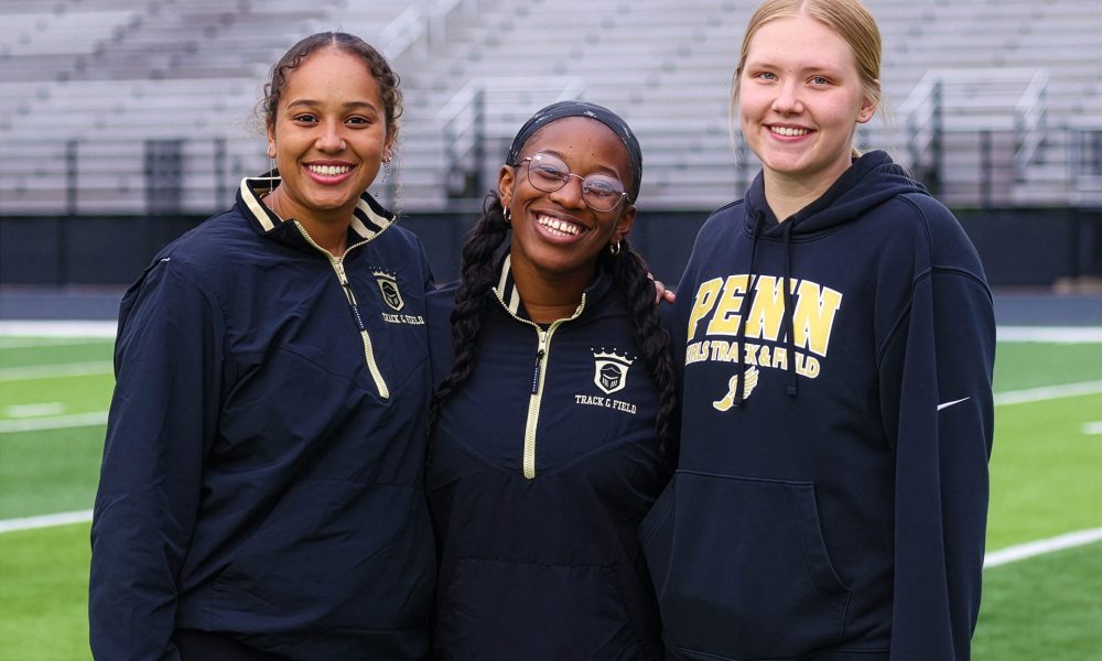 Three athletes posing on a track infield.