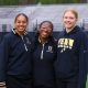Three athletes posing on a track infield.
