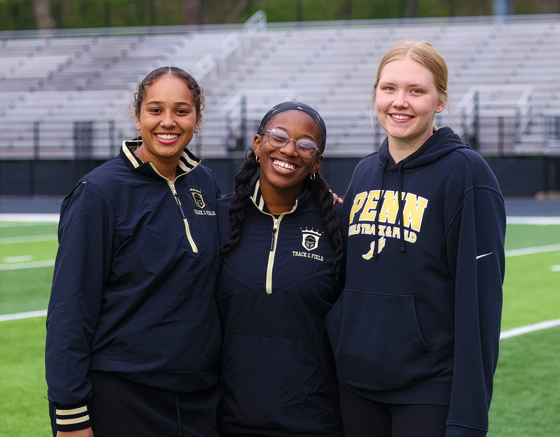Three athletes posing on a track infield.