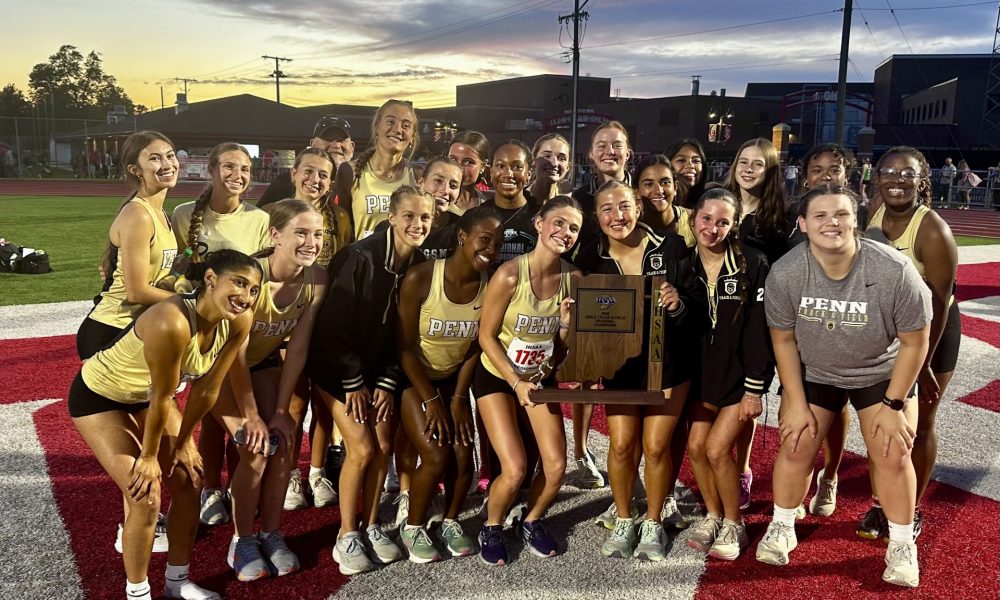 Team of track athletes posing for a team picture on a football field.