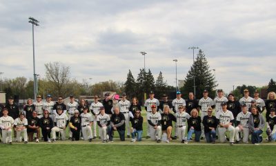 Baseball team posing for a group picture on field.