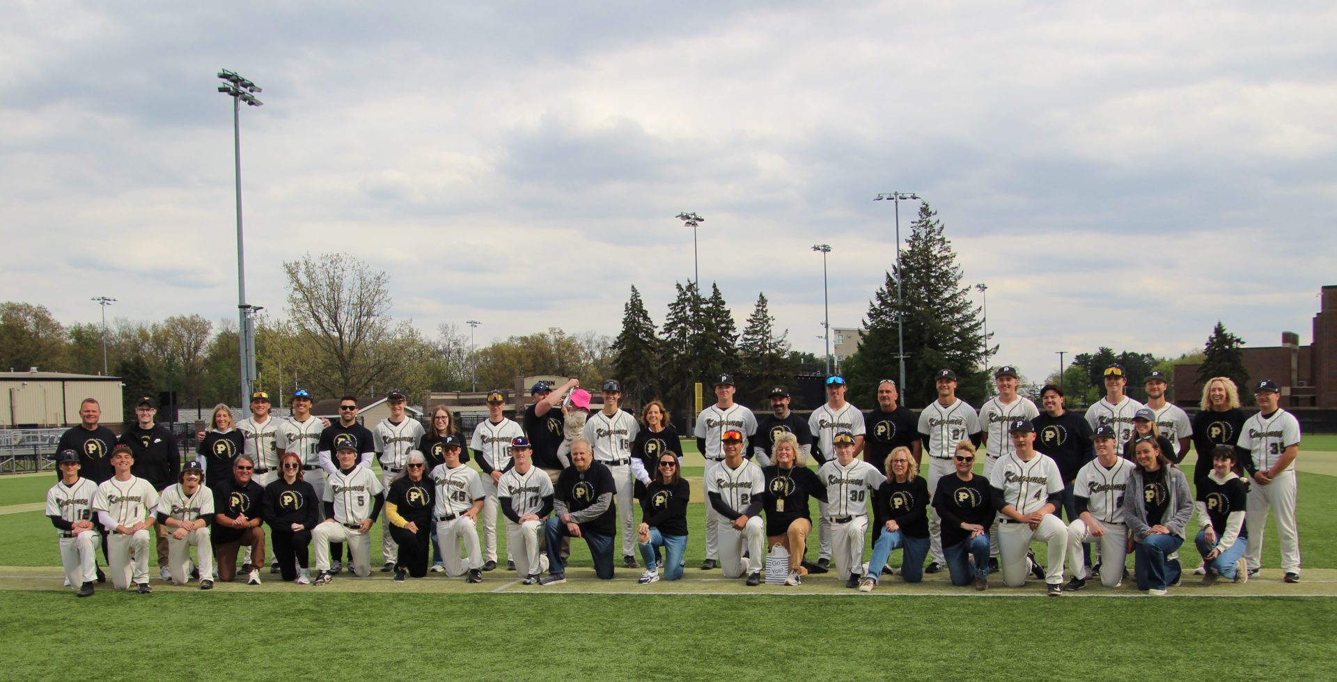 Baseball team posing for a group picture on field.