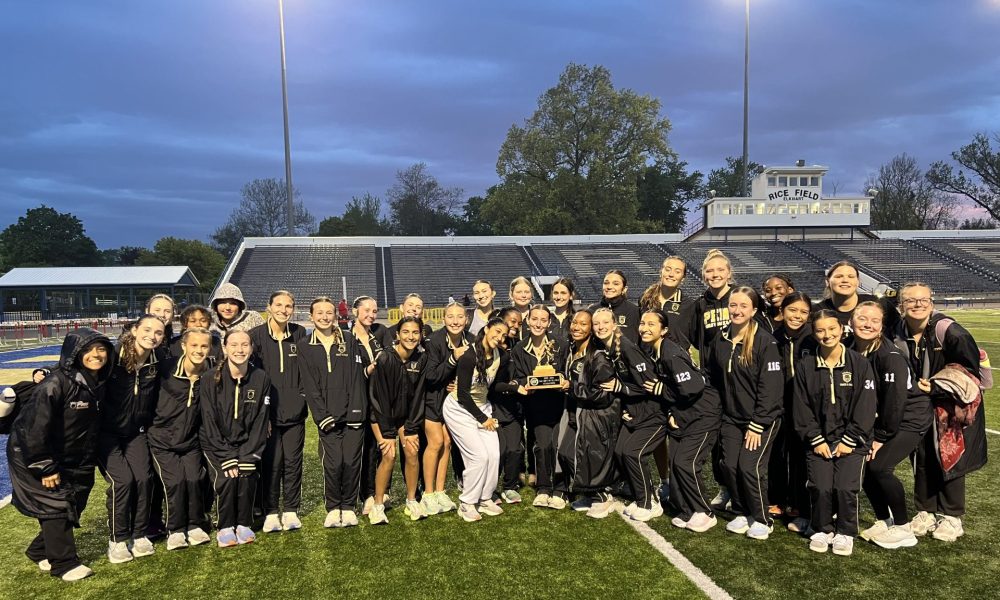 Penn Girls Track & Field team posing with a trophy on a track infield.
