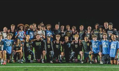 This is a team photo of a sports team posing for a picture on a field at night.