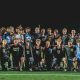 This is a team photo of a sports team posing for a picture on a field at night.