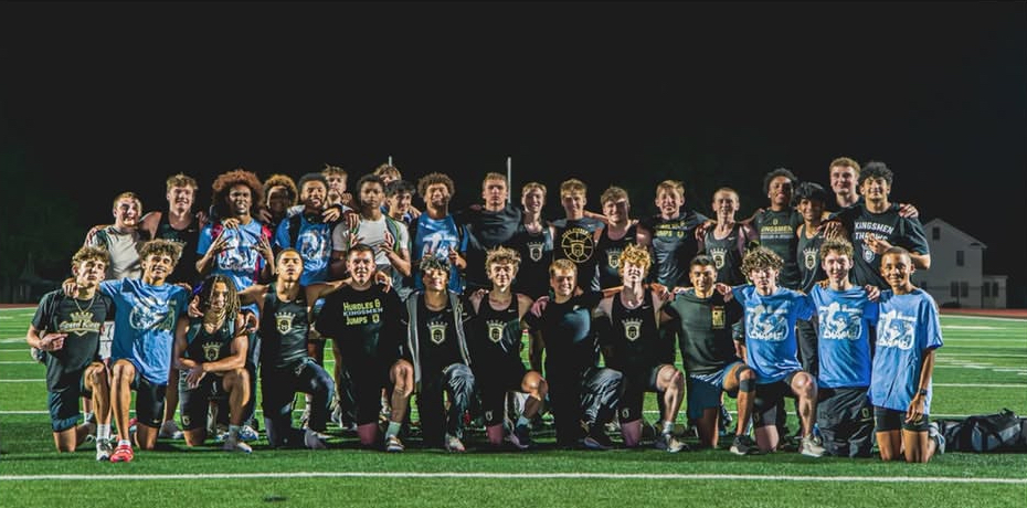 This is a team photo of a sports team posing for a picture on a field at night.